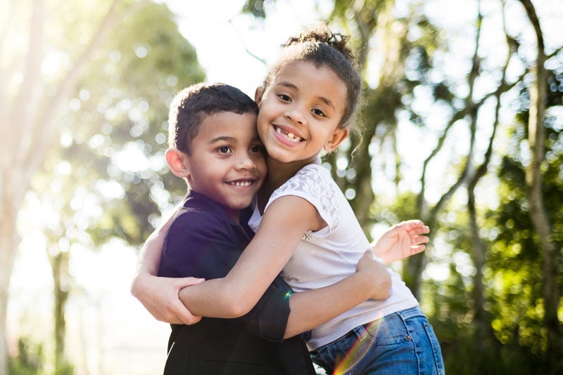 Brother and sister hugging in a park